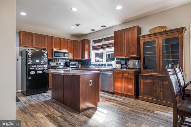 kitchen with appliances with stainless steel finishes, dark wood-type flooring, decorative backsplash, a sink, and recessed lighting