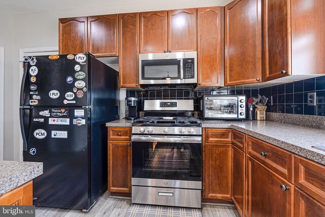 kitchen featuring appliances with stainless steel finishes, tasteful backsplash, and light wood-style floors