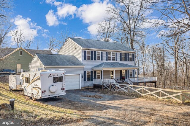 colonial inspired home featuring a porch, fence, a garage, a shingled roof, and dirt driveway