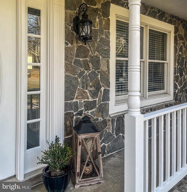 - property entrance featuring stone siding and covered porch