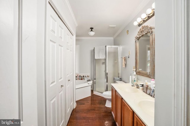 full bath with a stall shower, a sink, double vanity, crown molding, and wood finished floors
