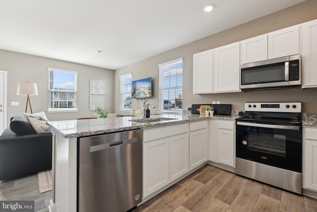 128 Rae Ct, Luray, VA 22835 - kitchen with appliances with stainless steel finishes, a peninsula, open floor plan, light wood finished floors, and white cabinets