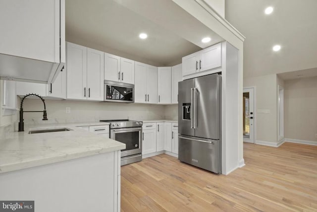 kitchen featuring appliances with stainless steel finishes, a sink, recessed lighting, white cabinetry, and light stone countertops