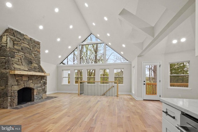 unfurnished living room featuring high vaulted ceiling, light wood-style flooring, a fireplace, and baseboards