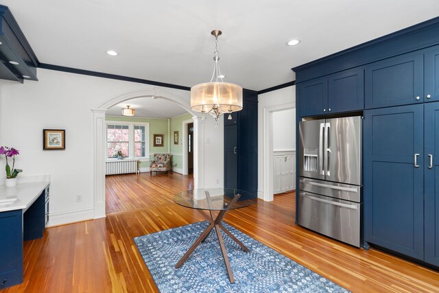 675 Beverley St E, Staunton, VA 24401 - kitchen with stainless steel fridge with ice dispenser, arched walkways, radiator heating unit, blue cabinetry, and light wood-style flooring