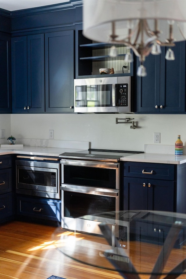 675 Beverley St E, Staunton, VA 24401 - kitchen featuring stainless steel appliances, blue cabinetry, light countertops, and wood finished floors