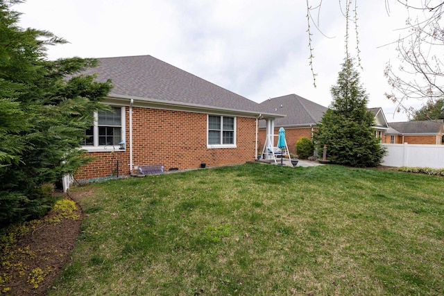 back of house with fence, brick siding, and a lawn