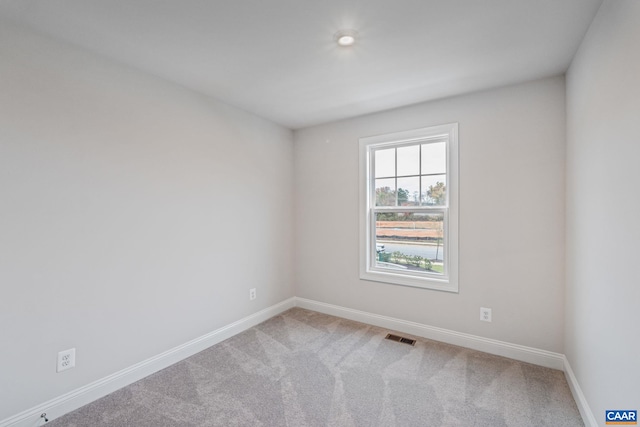 carpeted spare room featuring visible vents and baseboards