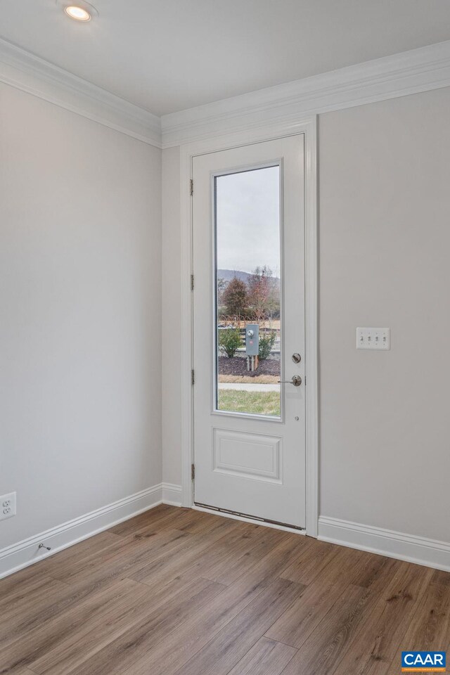 doorway to outside featuring crown molding, light wood-style floors, and baseboards
