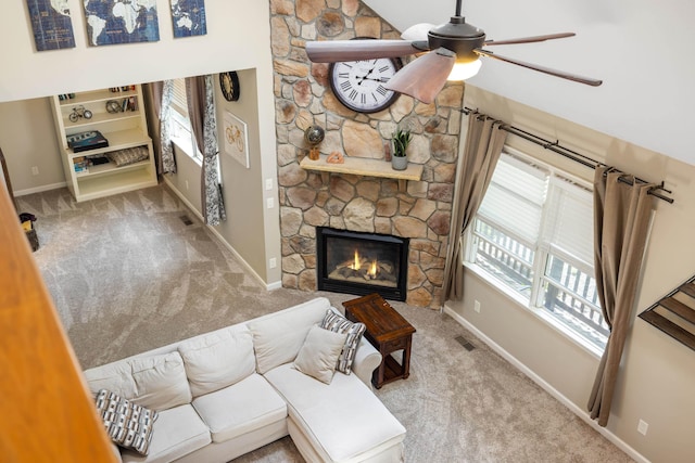 carpeted living area with baseboards, ceiling fan, and a fireplace