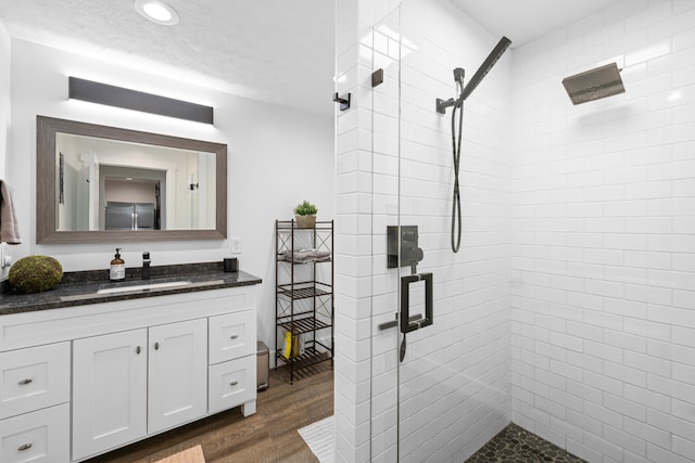 full bath with wood finished floors, tiled shower, vanity, and recessed lighting