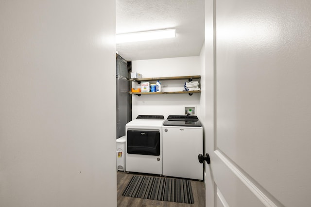 washroom with washing machine and clothes dryer, wood finished floors, and a textured ceiling
