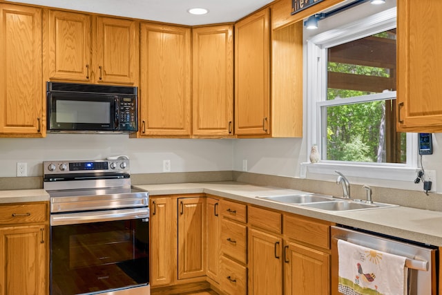 kitchen featuring appliances with stainless steel finishes, a sink, light countertops, and recessed lighting