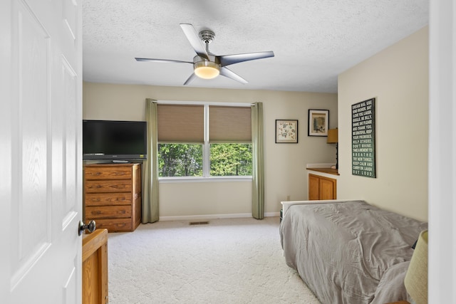 bedroom featuring light colored carpet, a textured ceiling, baseboards, and ceiling fan