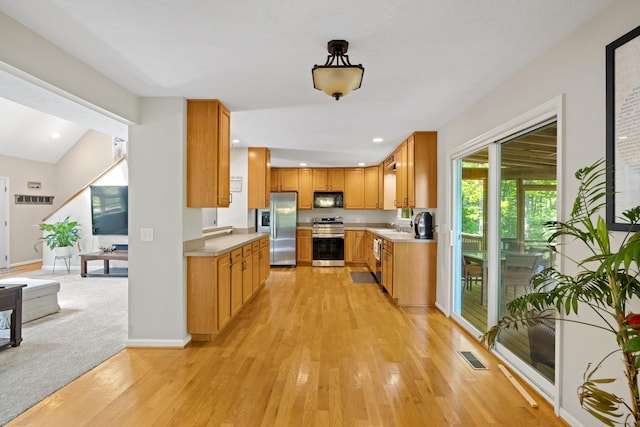 kitchen featuring stainless steel appliances, light countertops, light wood-style floors, a sink, and brown cabinets