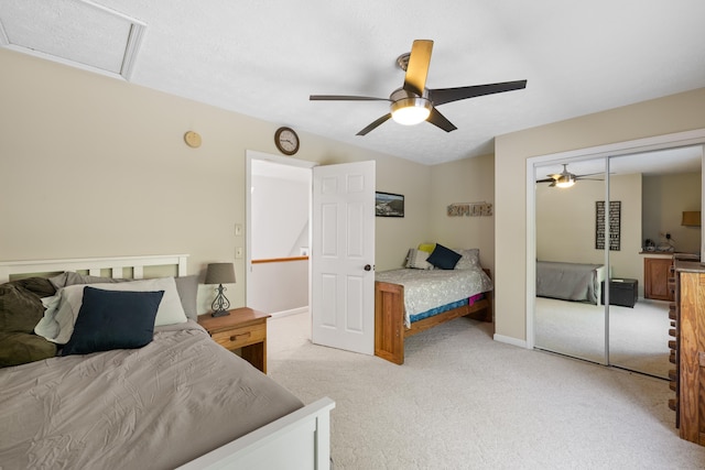 bedroom featuring light colored carpet, attic access, ceiling fan, a closet, and baseboards