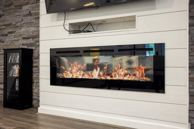 detailed view of wood finished floors and a glass covered fireplace