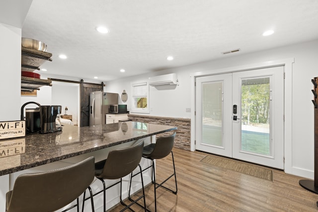 kitchen featuring an AC wall unit, a barn door, french doors, appliances with stainless steel finishes, and a breakfast bar