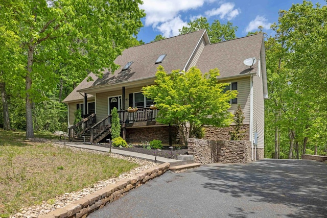 view of front of property with covered porch, a shingled roof, driveway, and stairs