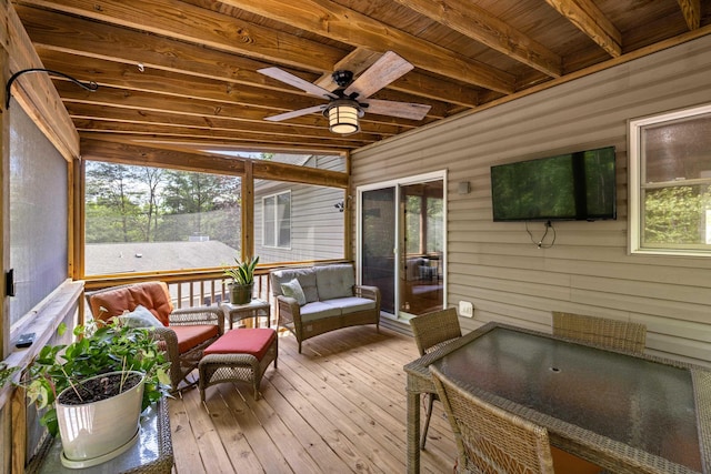 sunroom / solarium with ceiling fan, plenty of natural light, an outdoor living space, and beam ceiling