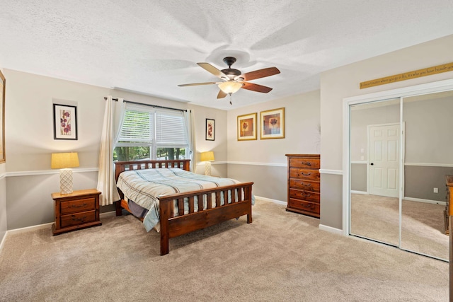 bedroom featuring a textured ceiling, carpet, a ceiling fan, a closet, and baseboards