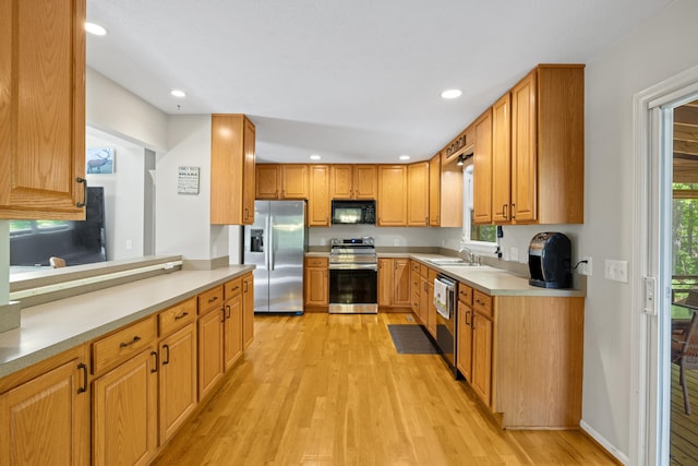 kitchen featuring stainless steel appliances, light wood-type flooring, a sink, recessed lighting, and plenty of natural light