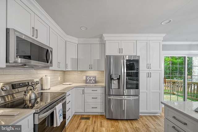343 Aspen Hill Rd, Mineral, VA 23117 - kitchen with appliances with stainless steel finishes, white cabinets, tasteful backsplash, light wood-type flooring, and crown molding