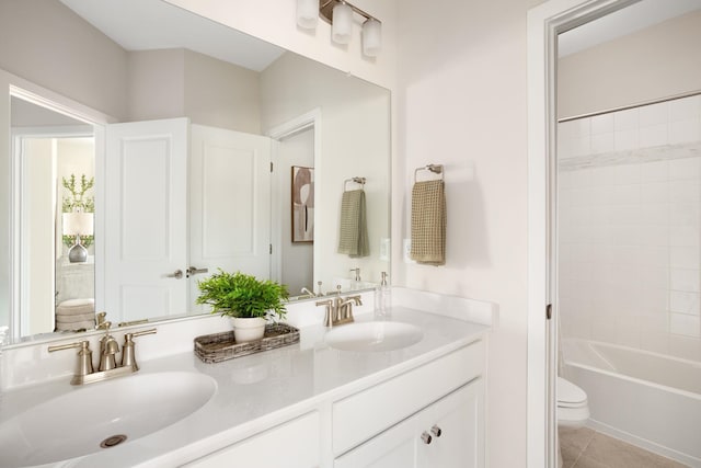 bathroom with a sink, tile patterned floors, toilet, and double vanity