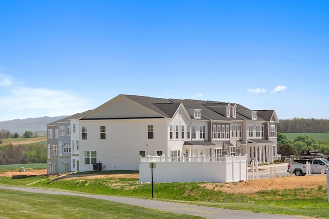 view of home's exterior with central AC, fence, and a mountain view