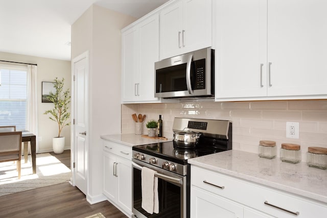 kitchen with decorative backsplash, light stone countertops, stainless steel appliances, and dark wood-style flooring