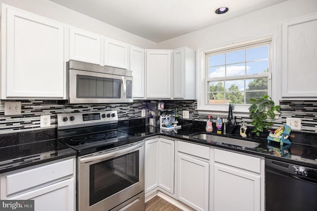 7504 Heathrow Dr, Fredericksburg, VA 22407 - kitchen featuring appliances with stainless steel finishes, a sink, decorative backsplash, dark stone counters, and white cabinets
