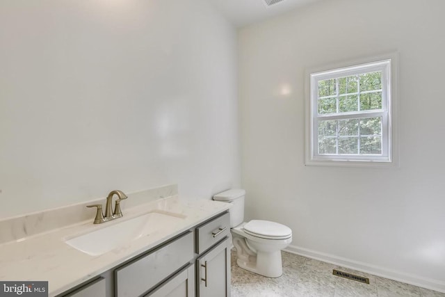 half bath with toilet, vanity, and baseboards