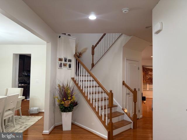 staircase featuring wood finished floors, baseboards, recessed lighting, and arched walkways