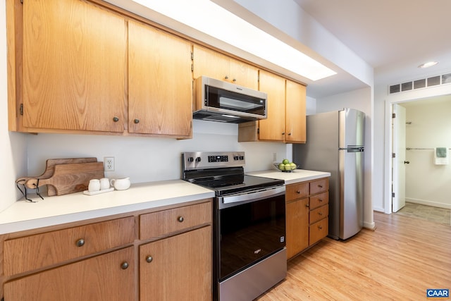kitchen with light wood finished floors, visible vents, baseboards, light countertops, and appliances with stainless steel finishes