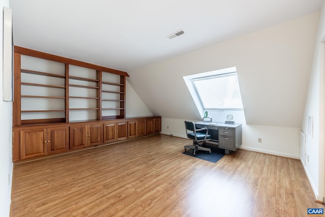 office space with baseboards, light wood finished floors, visible vents, and vaulted ceiling with skylight