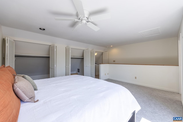 carpeted bedroom featuring attic access, two closets, baseboards, and a ceiling fan