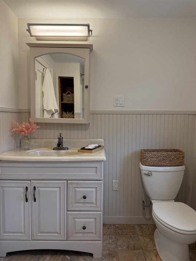 228 Hendren Ave, Staunton, VA 24401 - bathroom featuring vanity, toilet, a wainscoted wall, baseboards, and stone finish floors