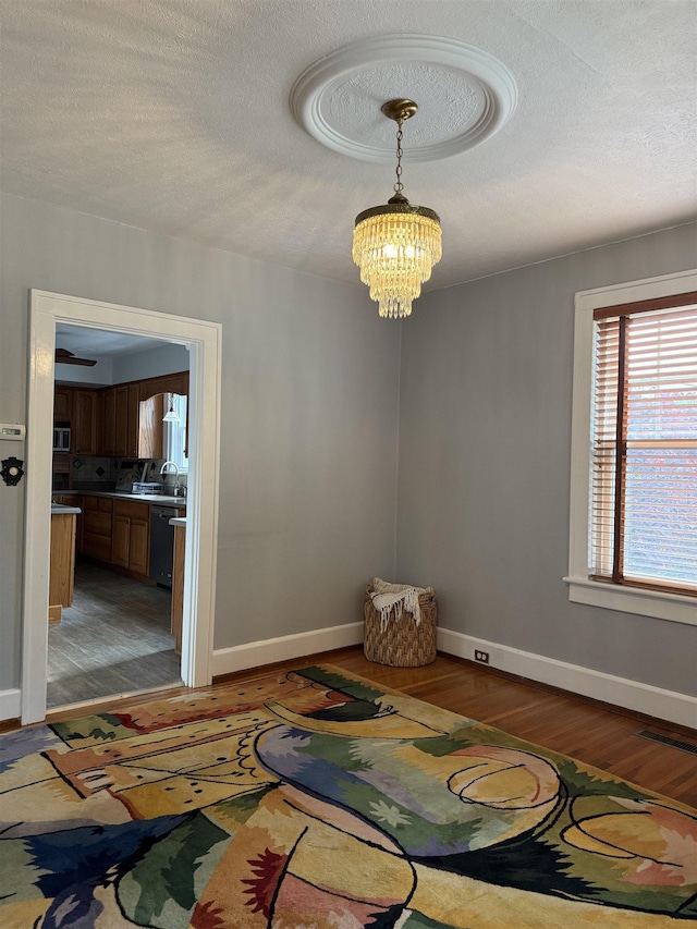 228 Hendren Ave, Staunton, VA 24401 - unfurnished room featuring light wood finished floors, a chandelier, baseboards, a textured ceiling, and a sink
