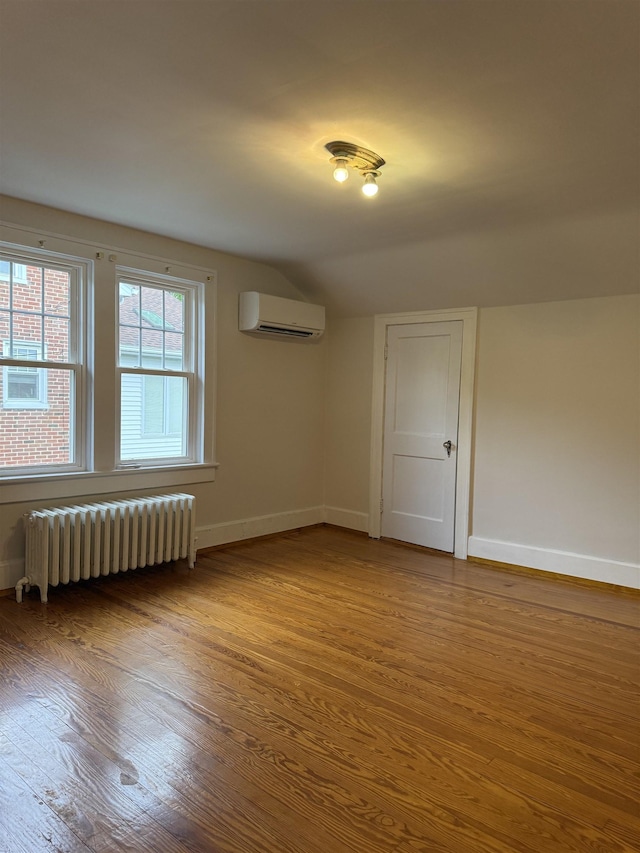 228 Hendren Ave, Staunton, VA 24401 - empty room featuring radiator, wood finished floors, an AC wall unit, baseboards, and lofted ceiling