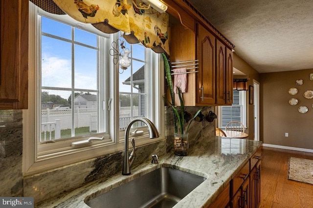 1066 Honeyville Rd, Stanley, VA 22851 - kitchen featuring a sink, brown cabinets, wood finished floors, baseboards, and a textured ceiling