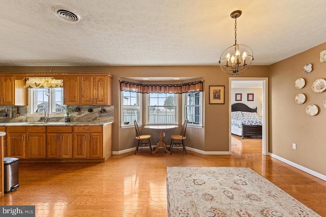 1066 Honeyville Rd, Stanley, VA 22851 - kitchen with a sink, brown cabinetry, a chandelier, plenty of natural light, and a textured ceiling