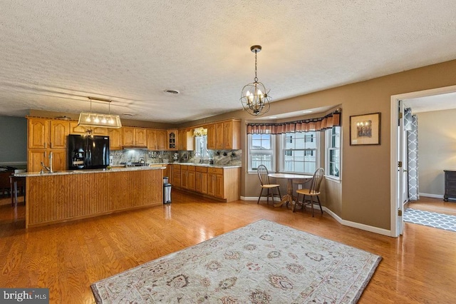 1066 Honeyville Rd, Stanley, VA 22851 - kitchen featuring black fridge with ice dispenser, a kitchen island with sink, a textured ceiling, a chandelier, and brown cabinets