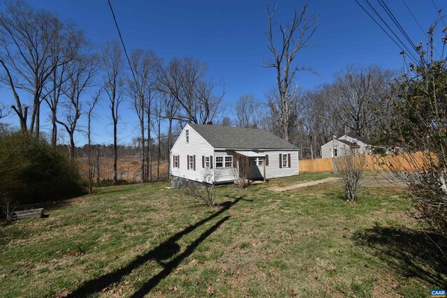 4490 James Madison Hwy, Gordonsville, VA 22942 - view of front facade featuring a front yard, an outbuilding, roof with shingles, and fence