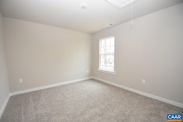 carpeted spare room featuring attic access, visible vents, and baseboards