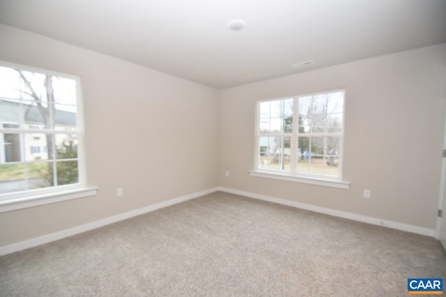 spare room featuring carpet, plenty of natural light, and baseboards