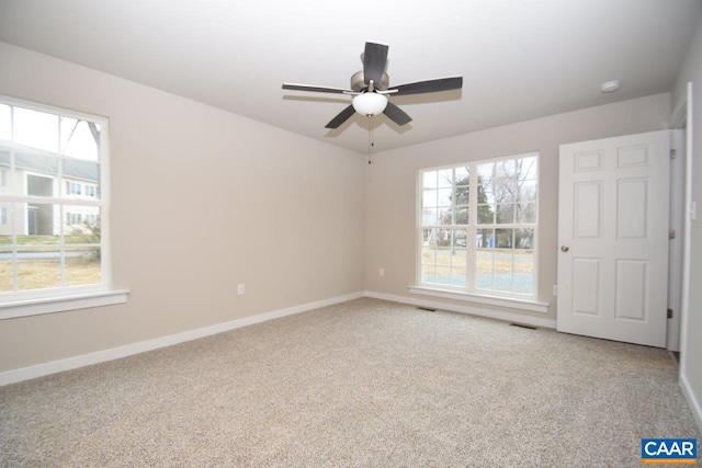 carpeted spare room featuring baseboards, visible vents, and a ceiling fan
