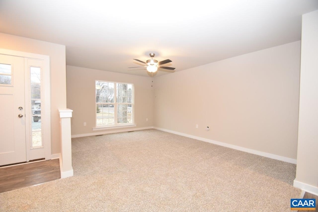 foyer entrance featuring a ceiling fan, light colored carpet, and baseboards