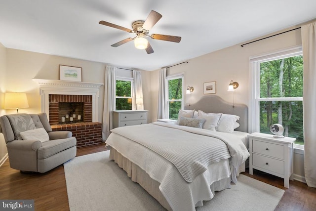  - bedroom with wood finished floors, multiple windows, a brick fireplace, and a ceiling fan
