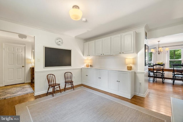  - living area featuring crown molding, light wood-type flooring, a chandelier, and baseboards