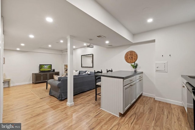  - kitchen with a breakfast bar, light wood finished floors, dark countertops, baseboards, and recessed lighting